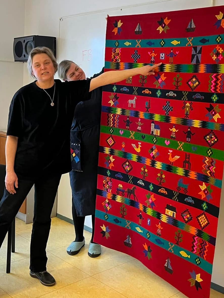 Christi Kütt with the participants of a weaving course and the wedding carpet. Photo by Eesti Rahvakunsti ja Käsitöö Liit.